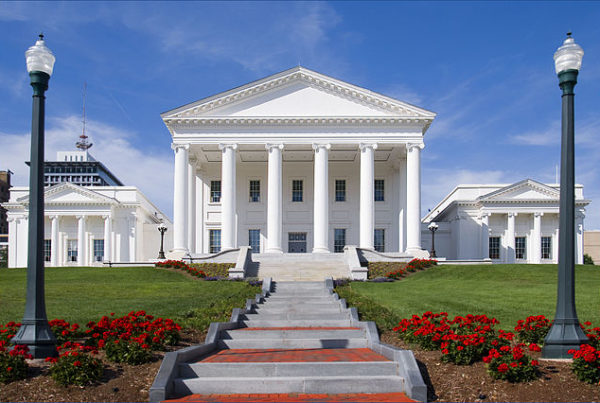red flowers and stone steps lead to the white columned building of the Virginia State Capitol